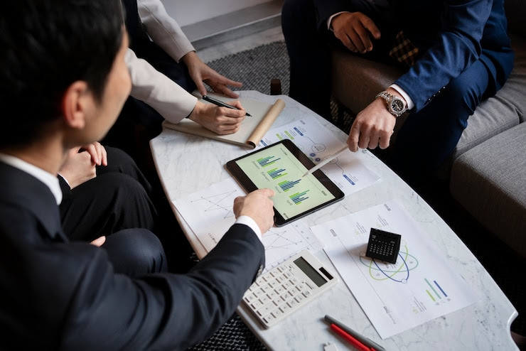 Business professionals discussing expansion strategies in Vietnam with graphs on a tablet and documents on a table.